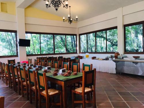 a dining room with a table and chairs and windows at Posada Los Colorines in Zinapécuaro de Figueroa