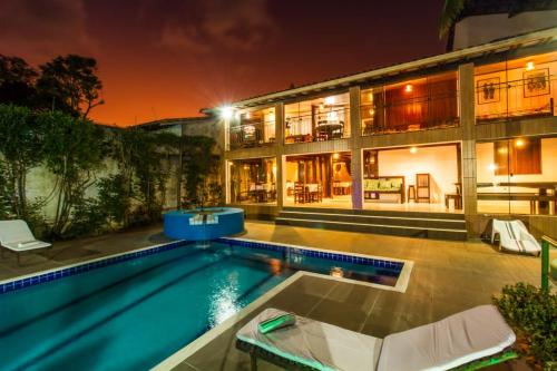a house with a swimming pool at night at Alto do Aeroporto Hotel in Porto Seguro