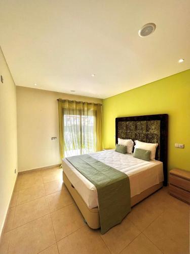 a bedroom with a large bed with a yellow wall at Funtastic Villa With Pool in Albufeira