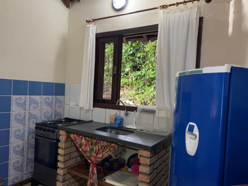 a kitchen with a sink and a blue refrigerator at Pousada Pé da Mata Maresias in Maresias