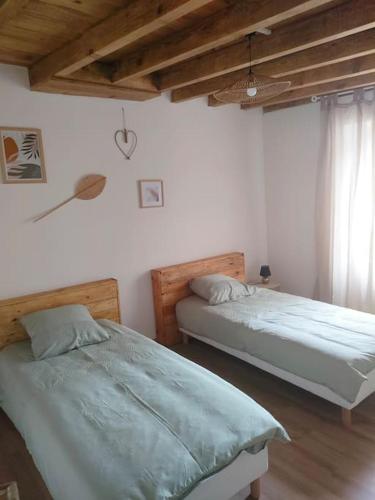 une chambre avec deux lits et une fenêtre dans l'établissement Gîte chaleureux au cœur du village, à Roquetaillade