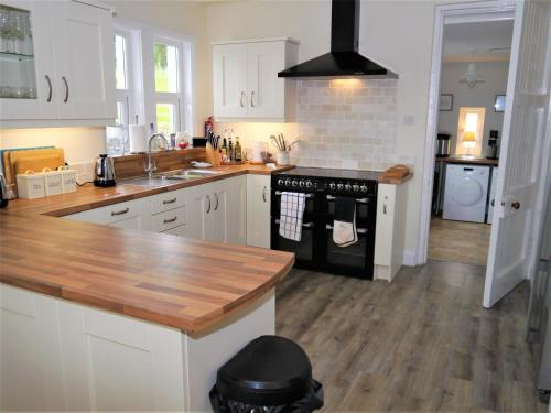 a kitchen with white cabinets and a black stove top oven at Glaisters Farmhouse in Castle Douglas