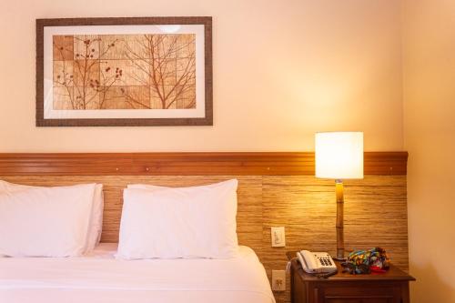 a hotel room with a bed and a phone on a table at Pousada Corsario Buzios in Búzios