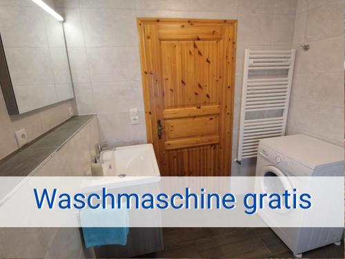 a bathroom with a sink and a wooden door at Böltser Hus Ferienwohnungen mit Strandkorb und Kamin 10 Gehminuten zum kurtaxefreien Sandstrand in Neukirchen