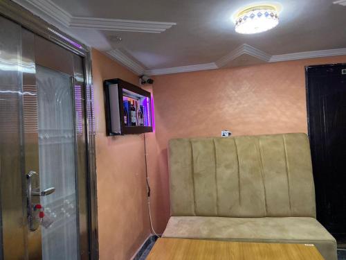 Habitación con silla y TV en la pared. en Oak Suites & Bar, en Benin City