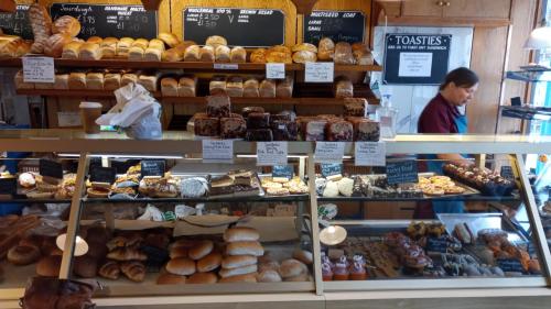 una mujer parada frente a una panadería con un montón de pasteles en Rosemoor view. en Great Torrington