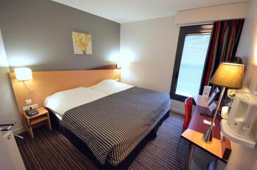 a hotel room with a bed and a window at Kyriad Hotel Dijon Gare in Dijon