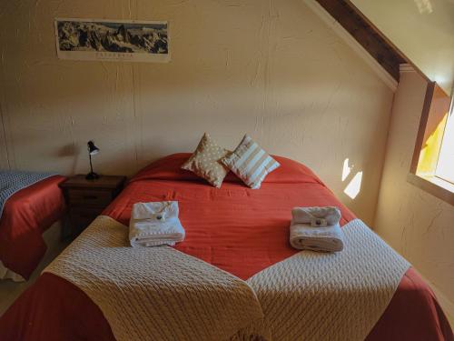 a bedroom with a red bed with towels on it at Los Lupinos in El Chalten