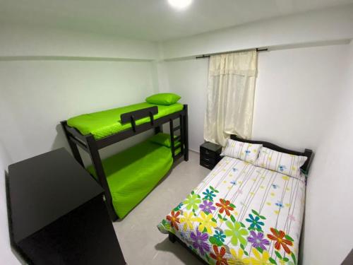1 dormitorio con litera verde y TV en Hospedaje Santa Rosa de Cabal - Apartamento, en Santa Rosa de Cabal