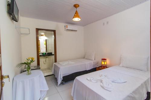 a room with two beds and a table and a mirror at Alto do Aeroporto Hotel in Porto Seguro