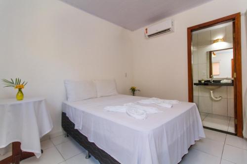a bedroom with a bed with white sheets and a mirror at Alto do Aeroporto Hotel in Porto Seguro