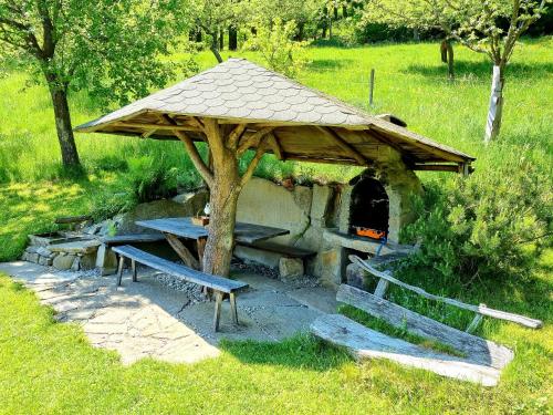 a picnic shelter with a table and benches in a field at Apartma1 pri Adamu in Mislinja