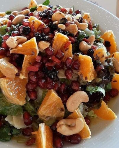 a white plate with a salad with fruit and nuts at Piccadilly in Alykes
