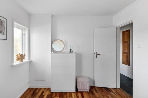 een witte kamer met een spiegel en een dressoir bij Peaceful family home with indoor fireplace in Åkersberga