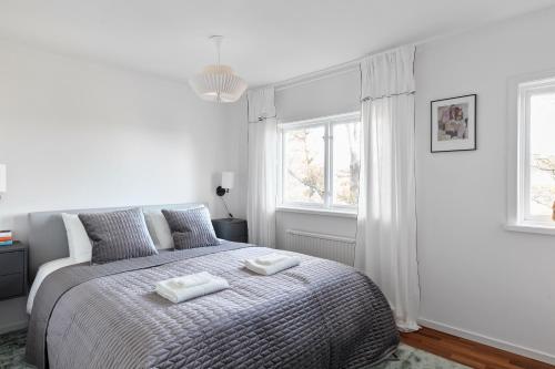 ein weißes Schlafzimmer mit einem Bett mit zwei Handtüchern darauf in der Unterkunft Peaceful family home with indoor fireplace in Åkersberga