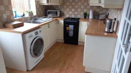uma cozinha com uma máquina de lavar roupa e um lavatório em Hamble Lounge - Accomodation for Aylesbury Contractors & Industrial estate - Free Parking & WIFI Sleeps up to 6 people em Buckinghamshire