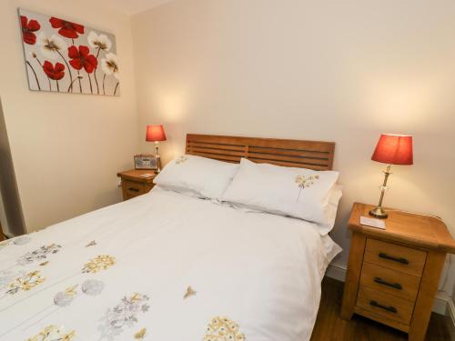 a bedroom with a bed and two night stands with lamps at Ty Taid in Gaerwen