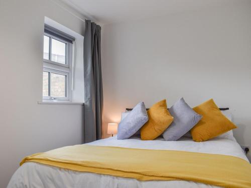 a bedroom with a bed with yellow and blue pillows at Pickwood Gatehouse in Leek