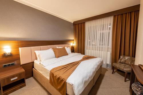 een slaapkamer met een bed, een bureau en een stoel bij Sapran Deluxe Hotel in Kars