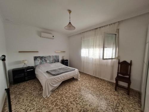 um quarto com uma cama e uma cadeira em AMPLIO CHALET CON GENIAL PISCINA A 10 MIN DE SEVILLA em Alcalá de Guadaira