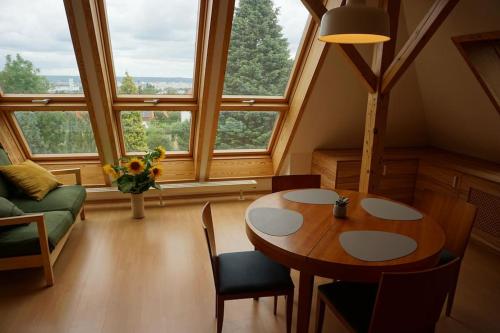 a living room with a table and chairs and windows at Apartment mit Ausblick im Dresdner Südwesten in Dresden