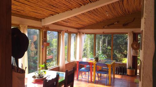 ein Esszimmer mit Fenstern sowie einem Tisch und Stühlen in der Unterkunft Granja Los Conejos in Ramiriquí