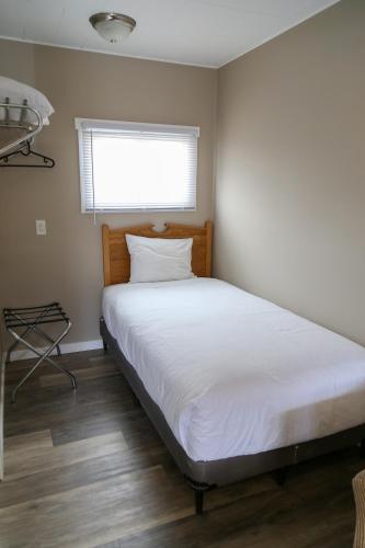 a bedroom with a white bed with a window at Richter Pass Beach Resort in Osoyoos