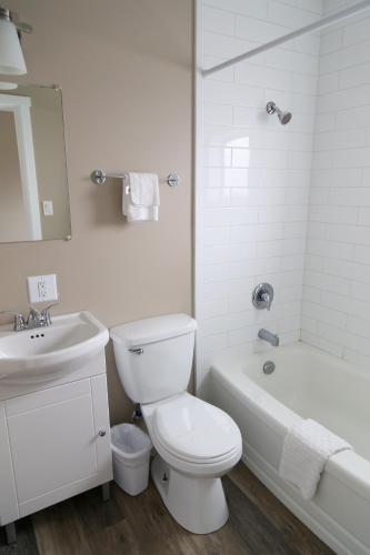 a white bathroom with a toilet and a sink and a tub at Richter Pass Beach Resort in Osoyoos