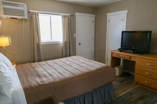 a bedroom with a bed and a flat screen tv at Richter Pass Beach Resort in Osoyoos
