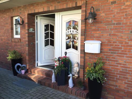 a front door of a brick house with potted plants at Nordseekrabbe Bollmann in Carolinensiel