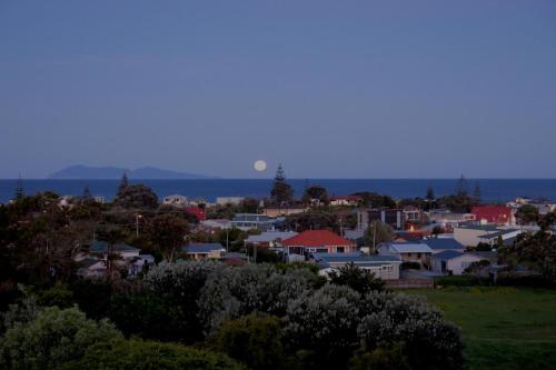 a view of a town with the moon in the sky at Atalaya in Waihi Beach