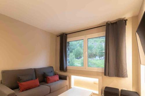 ein Wohnzimmer mit einem Sofa und einem Fenster in der Unterkunft Lovely quiet apartment walking distance ski runs in Soldeu