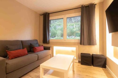 sala de estar con sofá y mesa en Lovely quiet apartment walking distance ski runs, en Soldeu