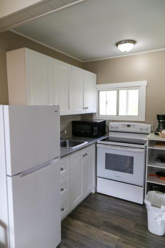 a kitchen with white cabinets and a white refrigerator at Richter Pass Beach Resort in Osoyoos