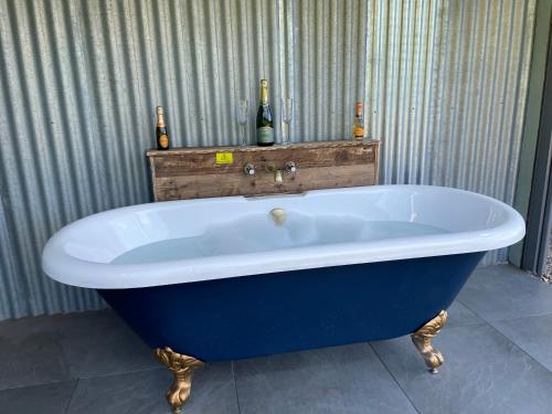 a blue tub in a bathroom with two bottles of wine at The Shepherd’s Nest in Bristol