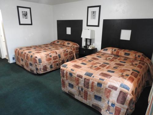 two beds in a hotel room with green carpet at Downtown Inn in Albuquerque