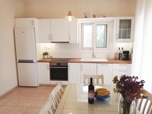 a kitchen with white cabinets and a table with a bottle of wine at Villa Katia in Tsoukaladhes