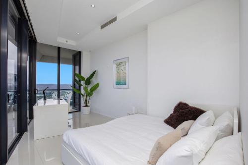 a white bedroom with a large bed with white pillows at Sub Penthouse Oracle 46th floor - GC Getaways in Gold Coast