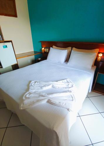 a bedroom with a bed with white sheets and pillows at Pousada Aquarela do Mar in Abraão