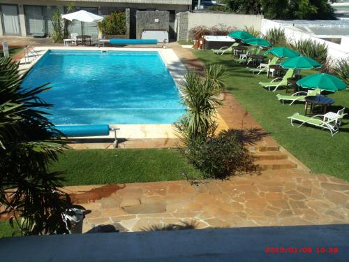 a swimming pool with chairs and umbrellas next to it at Hotel Puesta del Sol in Punta del Este