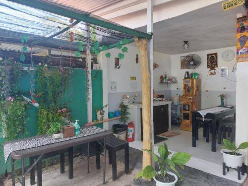 una habitación con mesas y una cocina con plantas en Maui's Place en Badian