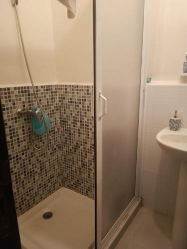 a shower with a glass door next to a sink at Appart bades 