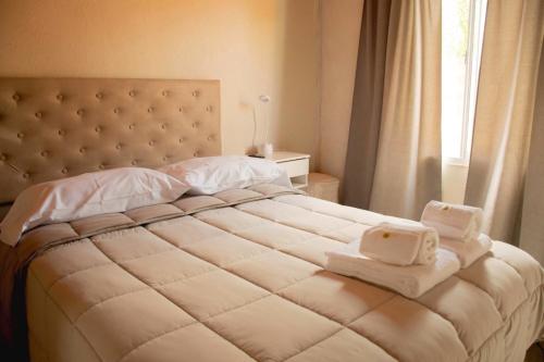 Un dormitorio con una gran cama blanca con toallas. en Vina, en Villa Elisa
