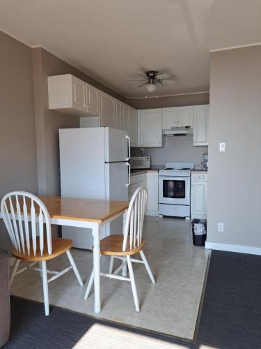a kitchen with a table and two chairs and a white refrigerator at Richter Pass Beach Resort in Osoyoos