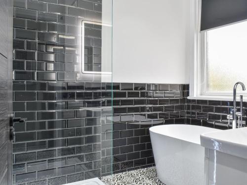 een zwart betegelde badkamer met een bad en een wastafel bij Hampton House in Blackpool