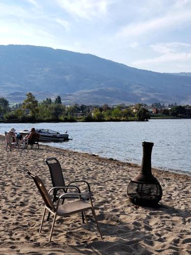 a beach with chairs and a boat in the water at Richter Pass Beach Resort in Osoyoos