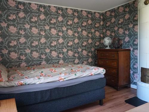 a bedroom with a bed and a wall with floral wallpaper at Holiday home RONNEBY IX in Ronneby