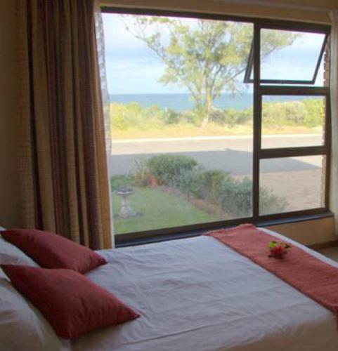 a bedroom with a bed and a large window at Dolphins View Self Catering Guesthouse in Duiwerivier