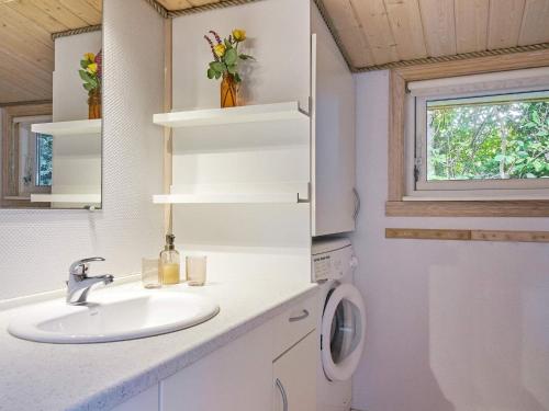 a bathroom with a sink and a washing machine at Holiday home Nexø XLI in Neksø