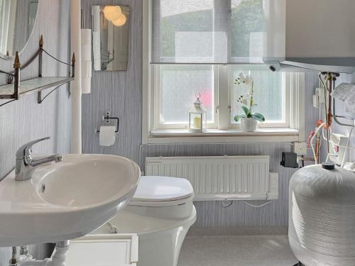 łazienka z umywalką, toaletą i oknem w obiekcie Holiday home öRSJö II w mieście Örsjö